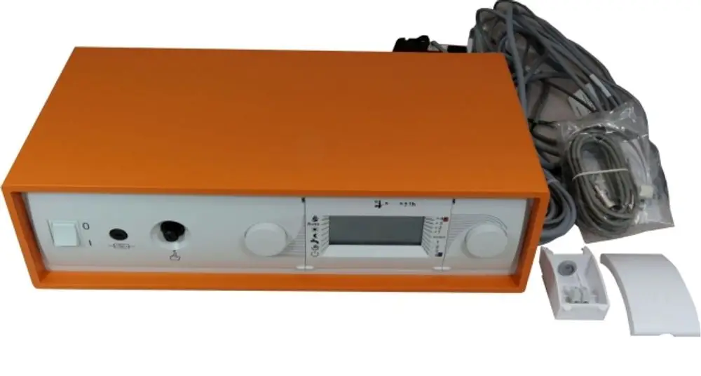 Wolf Regelungseinheit in orange für Heizsysteme, mit Hauptschalter, Anschlussbuchsen und Display zur Anzeige von Betriebsdaten. Kabelverbindungen liegen ebenfalls bereit.
